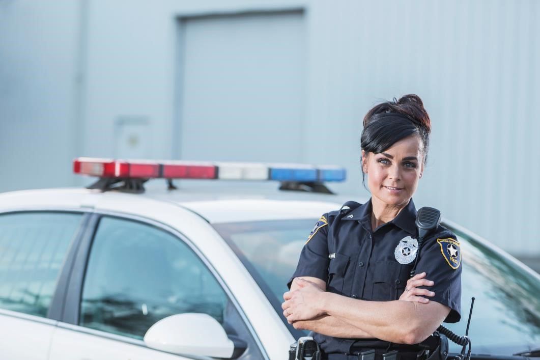 Woman police officer posing by her police car