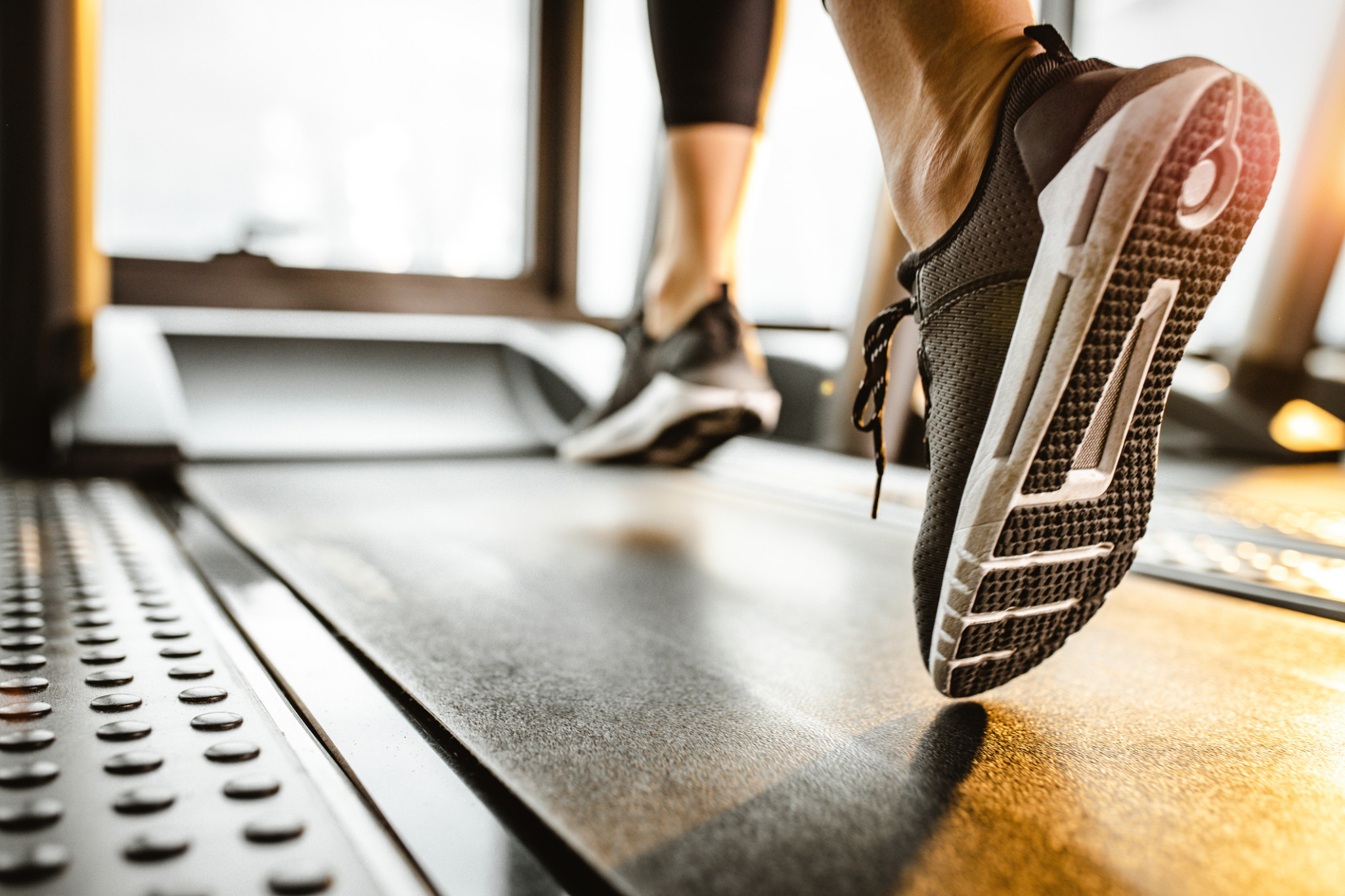 Insurance for Fitness Centers | Close up of sole of sneakers of unrecognizable athlete jogging on a treadmill.