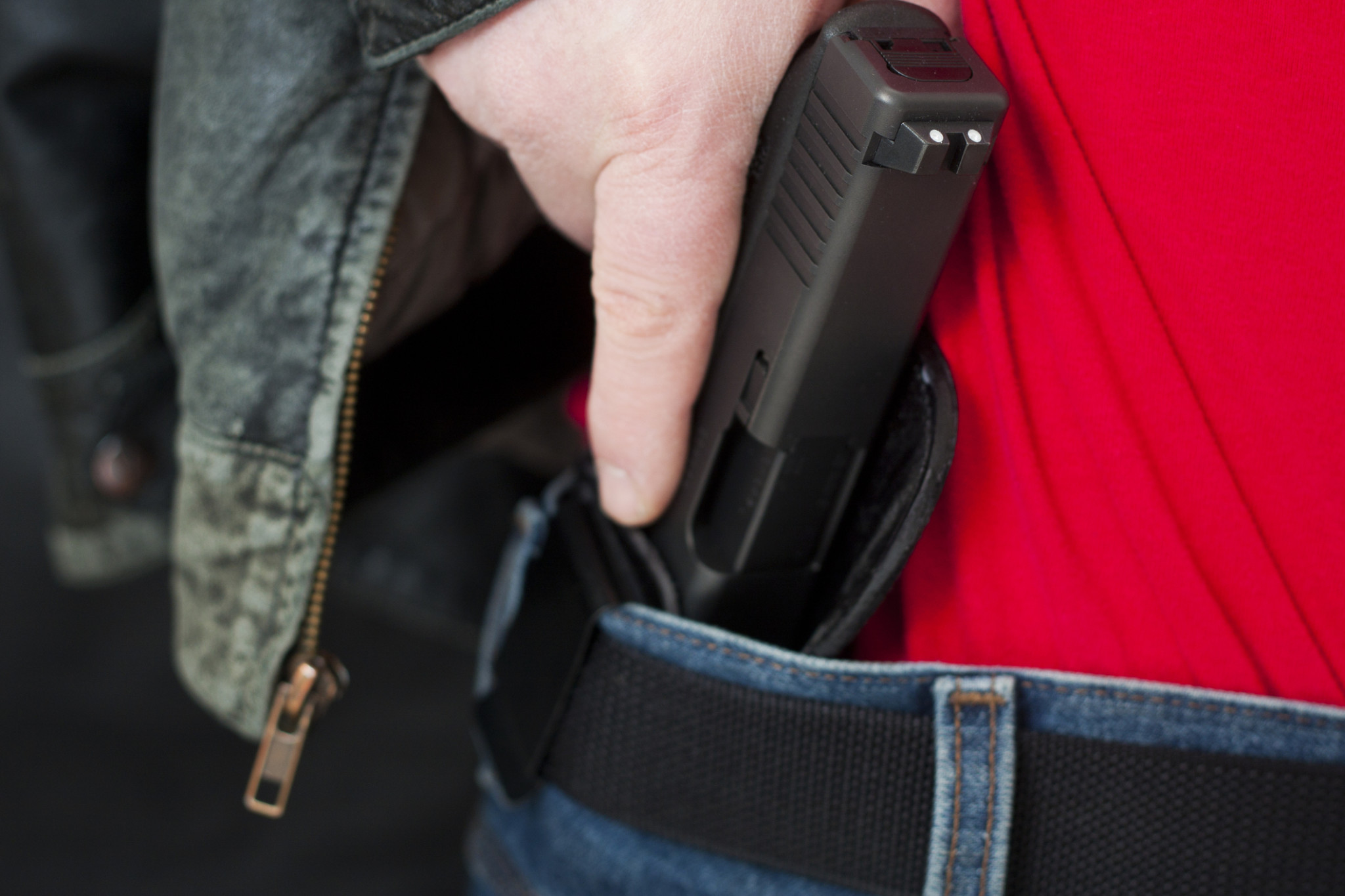 Man drawing pistol from holster under his jacket | Concealed carry insurance