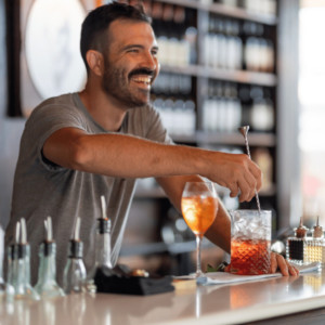 Smiling bartender mixing drink on counter